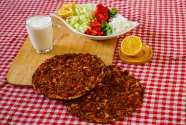 Turkish street food Lahmacun topped with fresh herbs and lemon