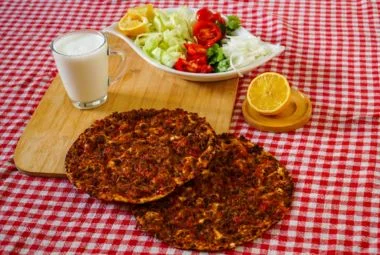 Turkish street food Lahmacun topped with fresh herbs and lemon